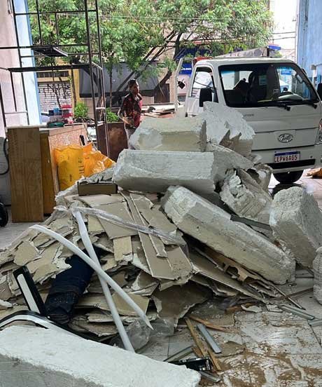 Caminhão VUC da Alencar Remoções carregando sacos brancos de entulho do canteiro de obras em São Paulo.